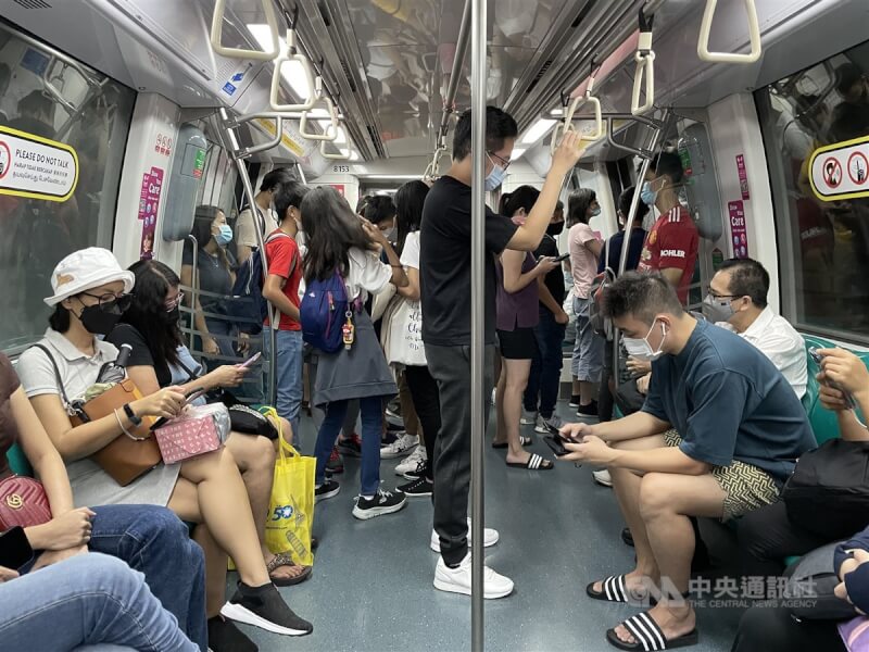 新加坡在4月底解除多數防疫措施。圖為4月新加坡民眾戴口罩搭乘地鐵。（中央社檔案照片）