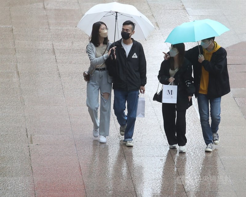 气象局表示，21日至25日受滞留锋影响，需防大雨。图为民众在台北市信义区周边百货购物，撑伞遮挡雨势。（中央社档案照片）