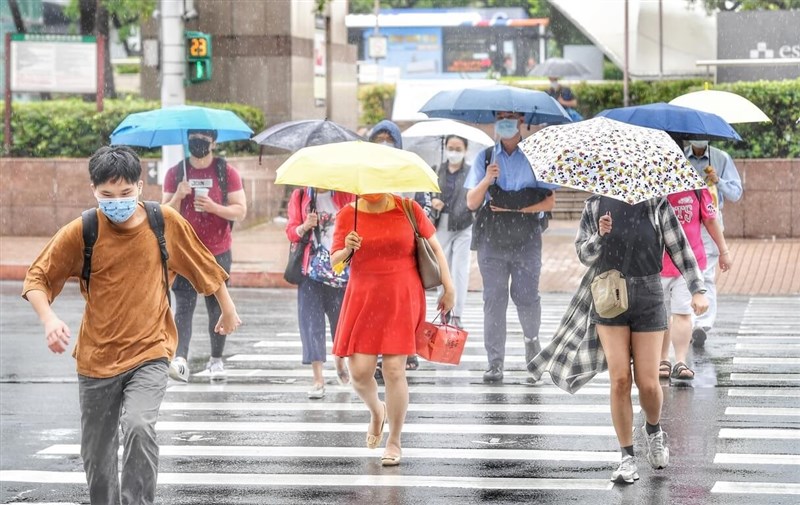氣象專家吳德榮表示，22日起鋒面報到，各地將有局部陣雨或雷雨機率。圖為台北車站前民眾撐傘快步過街。（中央社檔案照片）