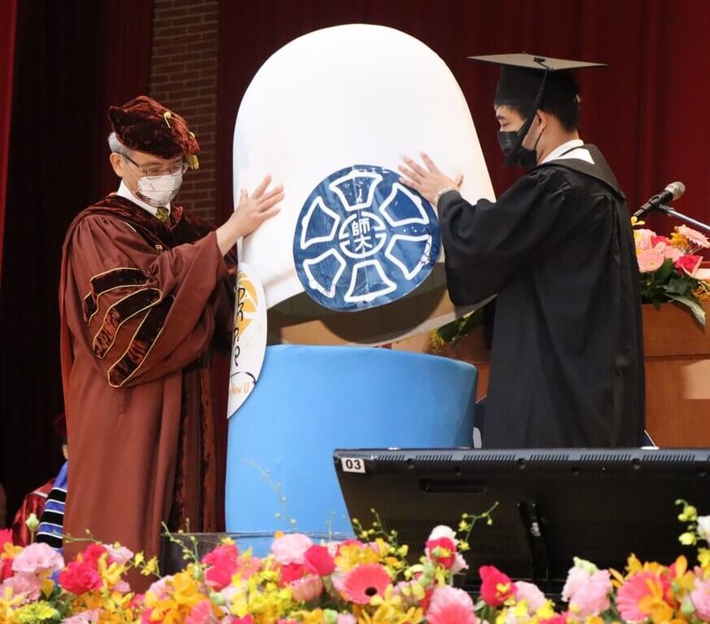 台灣師範大學校長吳正己(左)與畢業生代表張哲豪(右)21日在畢業典禮上共同揭開時光膠囊,取出每人在4年前伯樂大學堂寫下的「給未來的一封信」。(台師大提供)中央社記者許秩維傳真 111年5月21日