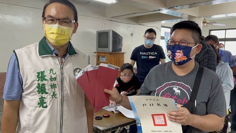 因應COVID-19疫情對經濟的衝擊,屏東縣九如鄉發放110年12月1日前設籍的鄉民每人新台幣1000元「振興經濟消費金」,23日發放首日,民眾持戶口名簿開心替家人領取千元現金。(民眾提供)中央社記者曾以寧傳真 111年5月23日