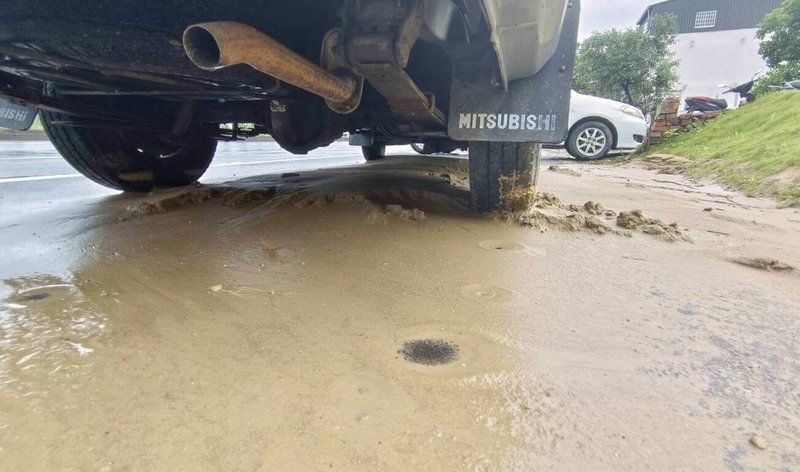 苗栗縣通霄鎮通灣里台1線旁一處工地25日晚間經大雨沖刷後,泥流湧入路面,造成4部機車打滑摔車,2人送醫幸無大礙,包商連夜清除,至26日仍可見泥土淤積。(民眾提供)中央社記者管瑞平傳真 111年5月26日