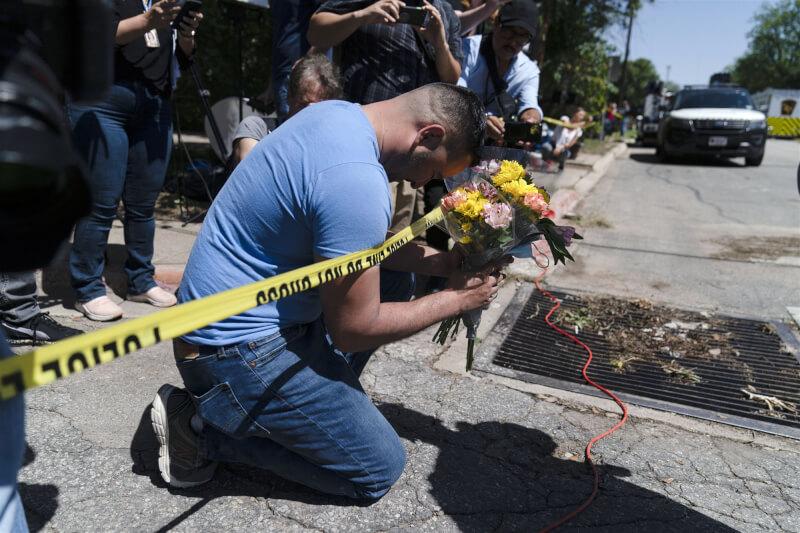 美國德州洛伯小學5月24日發生槍擊案，造成19名孩童和2名成人死亡。圖為民眾在案發小學前拿著花束為死者祈禱。（美聯社）