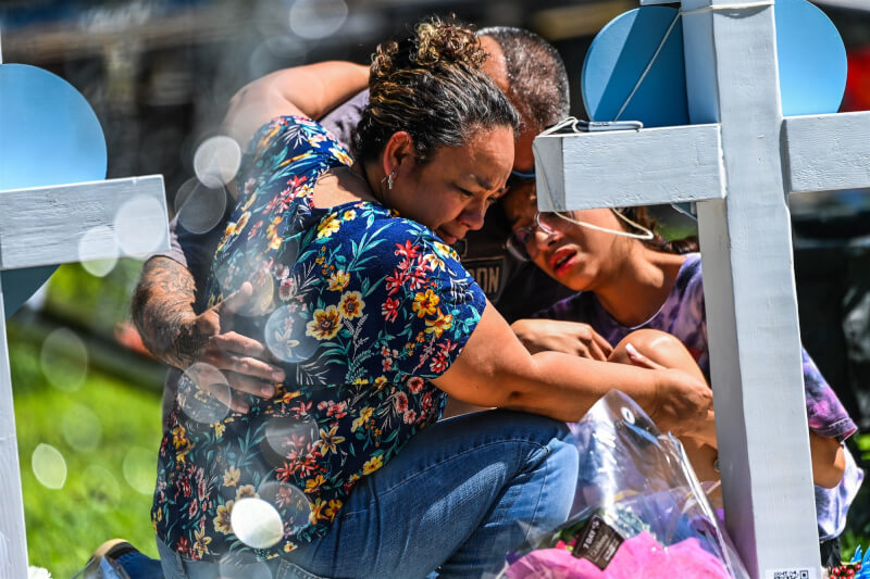 美國德州洛伯小學教師賈西亞在校園槍擊案中挺身保護學童，不幸殉職。圖為民眾26日在臨時紀念場為死者默哀。（法新社）