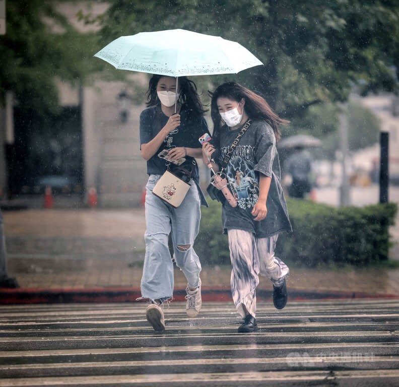 氣象局指出，31日受鋒面接近及西南風影響，天氣不穩定，凌晨苗栗以北有一波明顯雨勢。圖為台北大直街頭民眾雨中共撐一傘，快跑過馬路。（中央社檔案照片）