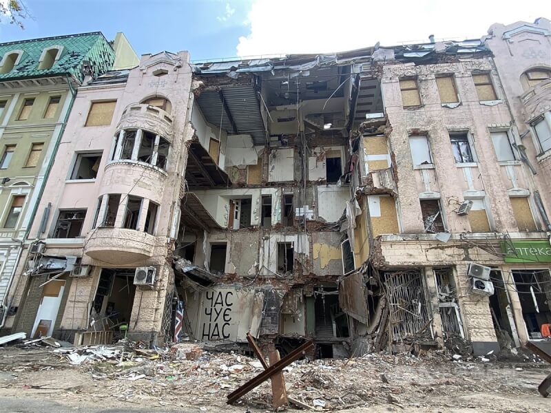 圖為烏克蘭東部第一大城哈爾科夫一棟建築遭毀,上面有一處以烏克蘭文寫著「時間療癒我們」。中央社記者鍾佑貞哈爾科夫攝 111年6月2日