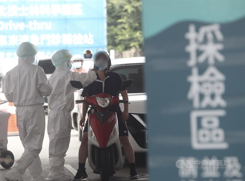 圖為5月23日醫護人員身穿全套防護裝備幫民眾做PCR採檢。(中央社檔案照片)