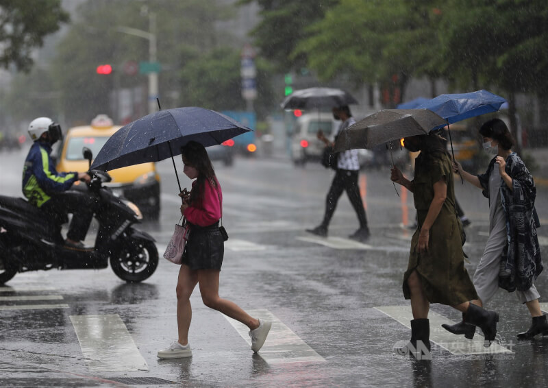氣象專家吳德榮表示，8日至12日滯留鋒在台灣南北徘徊，各地防劇烈天氣。圖為台北市內湖區下起大雨，民眾撐傘快步過馬路。（中央社檔案照片）