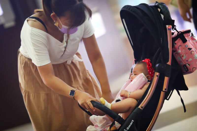 圖為新北市板橋區街頭一名家長細心照顧嬰兒車裡的幼兒。（中央社檔案照片）