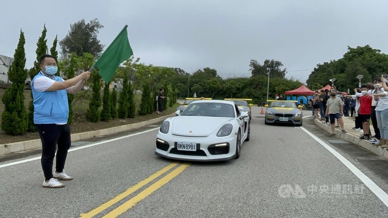 金門首場賽車賽事11日在后湖海濱公園登場,在縣府觀光處長丁健剛(左)揮旗下,50名車手陸續上路,往金城翟山、古崗、文台寶塔等景點沿途馳聘。中央社記者黃慧敏攝 111年6月11日
