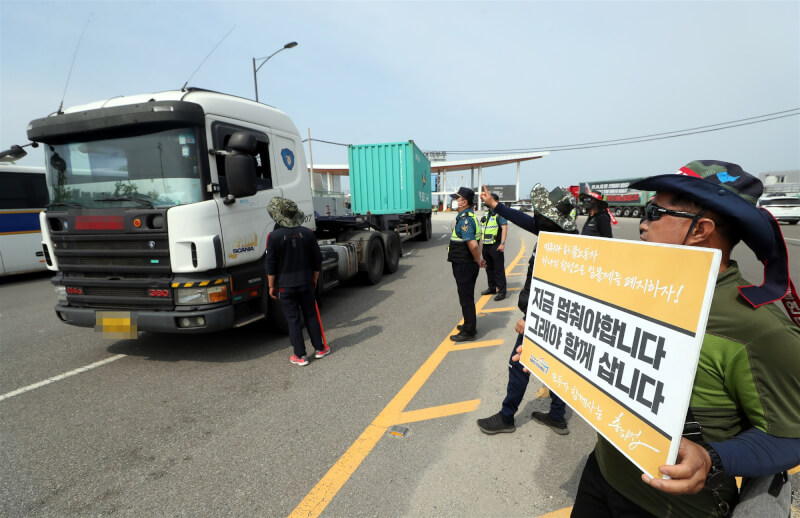 韓國貨車司機工會與政府達共識，司機們15日起將回到工作崗位。圖為貨運卡車司機團結工會成員8日在仁川區碼頭附近手持標語支持罷工。（韓聯社）