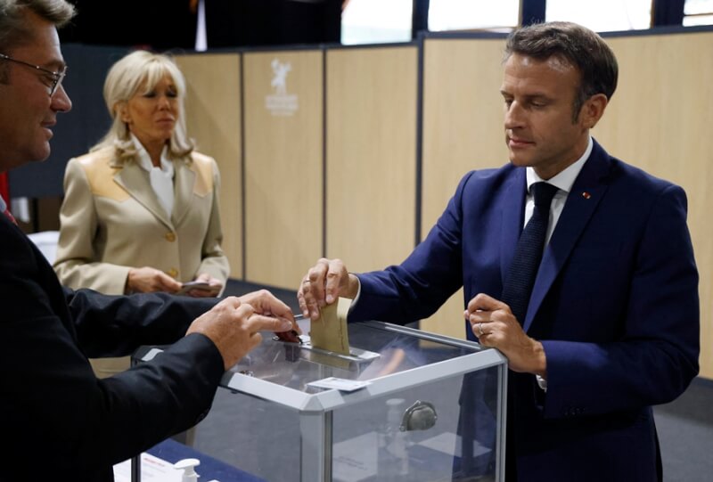 法國國會下議院國民議會選舉首輪投票12日登場。根據最新估票結果，梅蘭雄領軍的左翼聯盟得票率小贏執政黨同在聯盟。圖為法國總統馬克宏（右）投票畫面。（法新社）