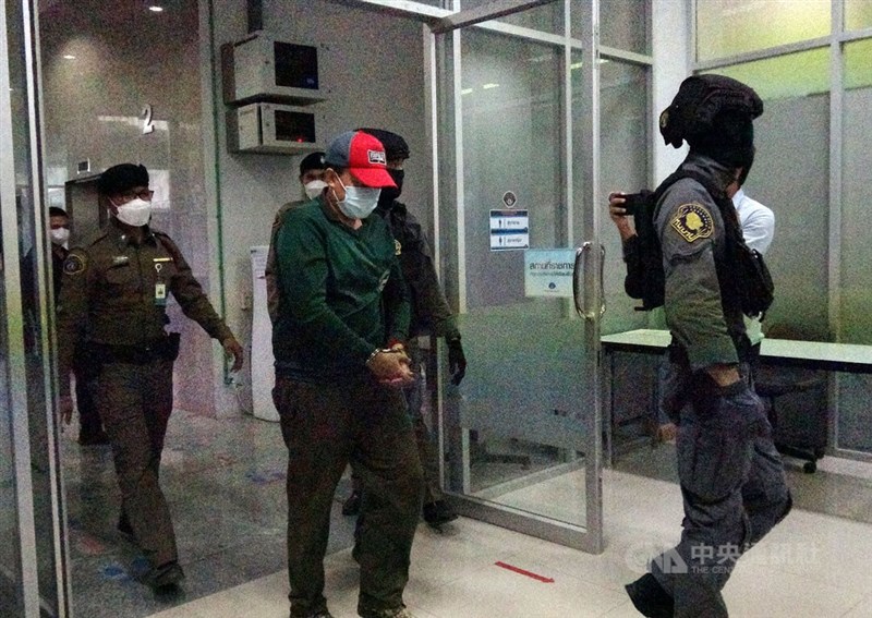 在台灣犯下雙屍命案的王姓嫌犯（紅帽者）逃回泰國，17日在清邁向警方投案。泰國警方表示，包括王嫌在內共有3人涉案。圖為王姓嫌犯被警方帶到曼谷的犯罪防治處。（中央社檔案照片）