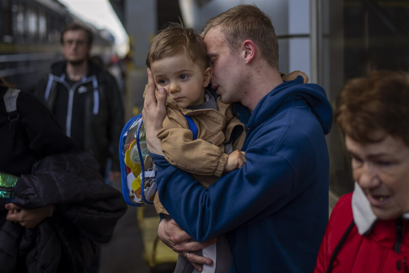 烏克蘭總統澤倫斯基19日在社群媒體上傳10張感人照片，顯示父母與孩子在無情戰火下的悲歡離合。圖為烏克蘭一名父親在火車站與自己的兒子重逢。（美聯社）