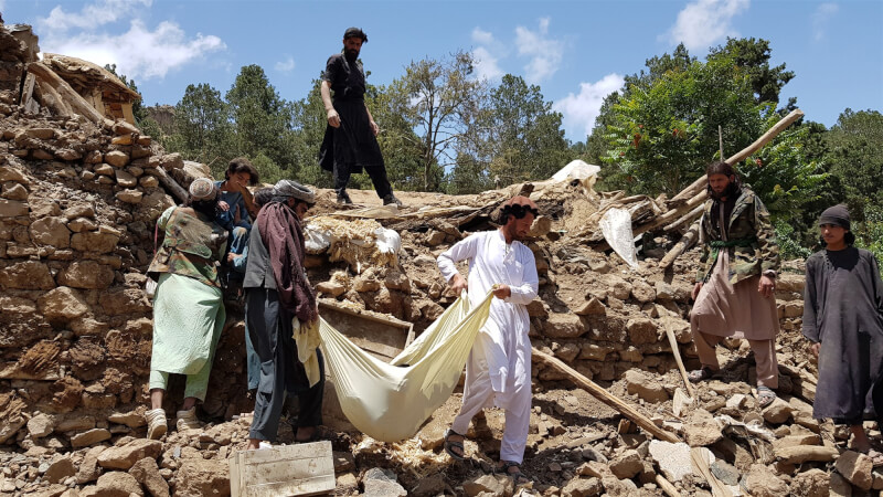 阿富汗東部22日凌晨遭受強震重創，至少千人罹難與數千人頓失家園。救援人員以布料當擔架搬運罹難者遺體。（安納杜魯新聞社）