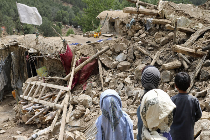 阿富汗22日發生強震，至少千人喪生。圖為當地兒童望著被地震摧毀的房屋。（美聯社）