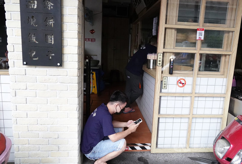台北市南港區24日下午發生停電狀況,忠孝東路6段、昆陽街、南港路3段、市民大道7段附近共265戶停電,受影響商家店內一片黑,無法營業,店員只能在門口有光處滑手機。中央社記者鄭傑文攝 111年6月24日
