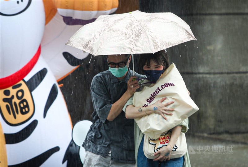 中央氣象局表示，週末高壓東退，25日午後雷陣雨發展可能比24日更劇烈。圖為台北市信義區民眾在大雨中共撐一把傘。中央社記者王騰毅攝 111年6月24日