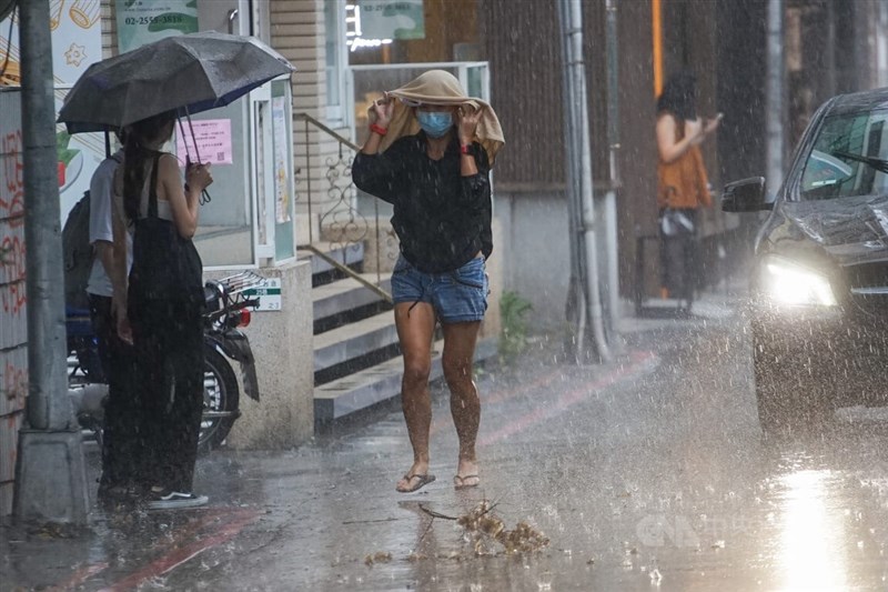 中央氣象局25日針對19縣市發布豪雨及大雨特報。圖為台北市中山商圈下午突然下起大雨，路上民眾措手不及，以衣服遮擋雨勢。中央社記者裴禛攝 111年6月25日