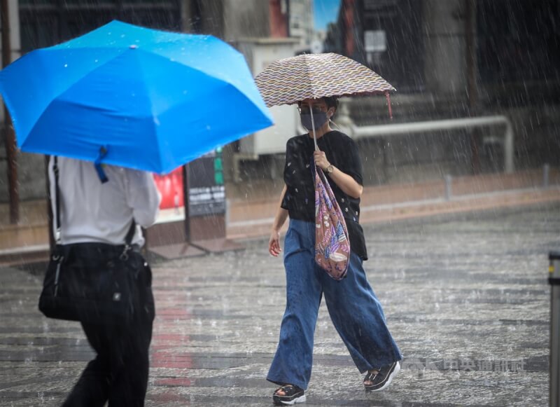 中央氣象局25日中午針對17縣市發布大雨特報。圖為台北市信義區民眾撐傘避雨。（中央社檔案照片）