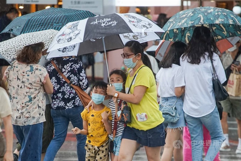 氣象專家吳德榮表示，27至30日需注意攝氏36度以上高溫及午後大雷雨。圖為民眾25日下午到台北市中山商圈逛街遇到大雷雨，撐傘摟住孩子快步過馬路。（中央社檔案照片）