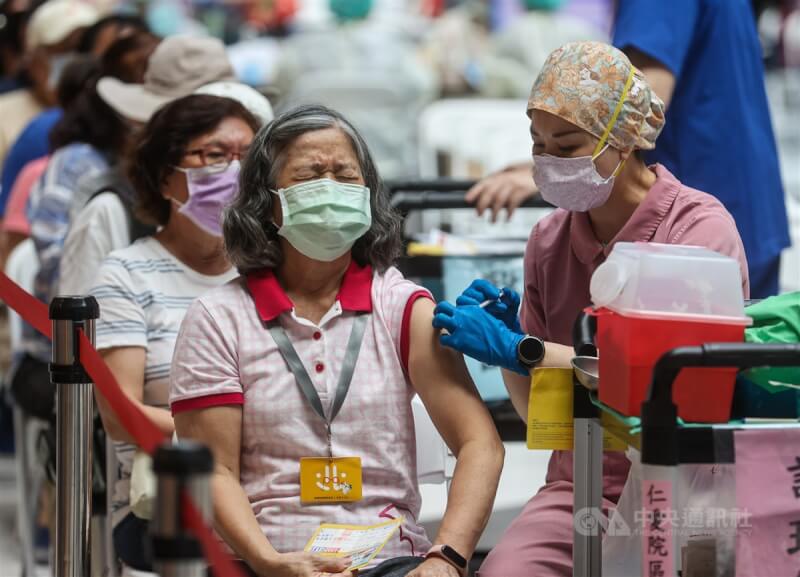 國內27日新增2萬8489例COVID-19本土病例。圖為民眾在台北車站疫苗接種站挽起袖子施打疫苗。（中央社檔案照片）