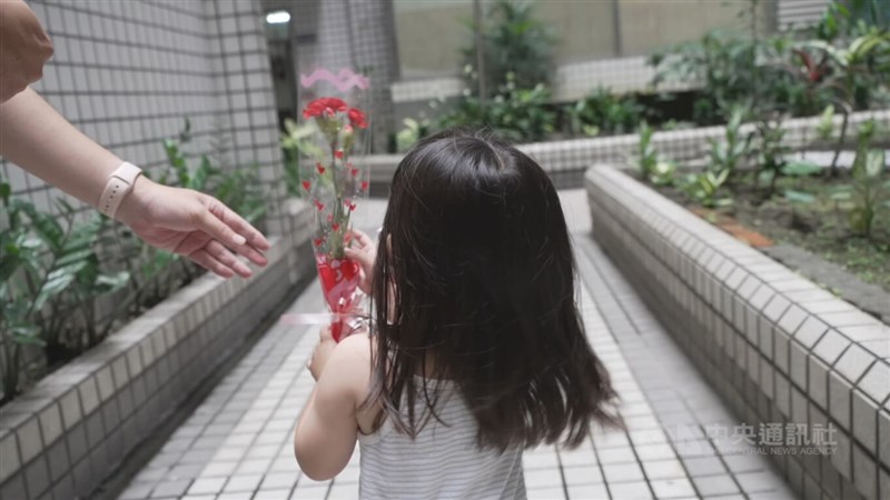 台灣同志伴侶圍圍、喵喵收養的女兒肉肉手拿康乃馨。中央社記者張智彥高雄攝 111年6月28日