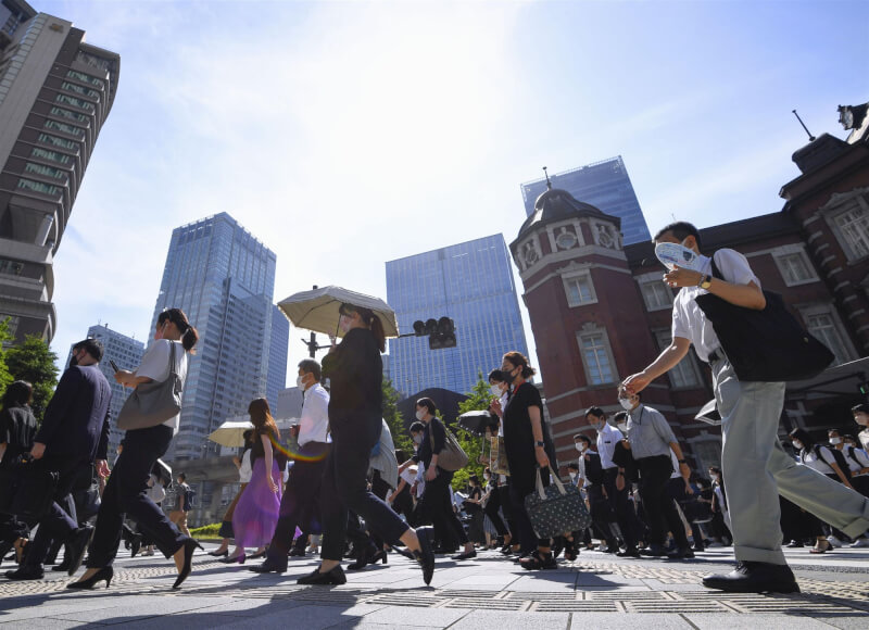 日本東京連續6天出現逾35度的「猛暑日」。圖為30日東京車站前有行人撐傘防烈陽。（共同社）