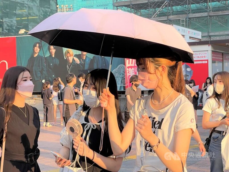 東京市中心1日觀測到攝氏37度,連7天達攝氏35度的猛暑日。圖為6月29日東京澀谷,傍晚也酷熱,有些人拿小風扇、撐傘。中央社記者楊明珠東京攝 111年7月1日