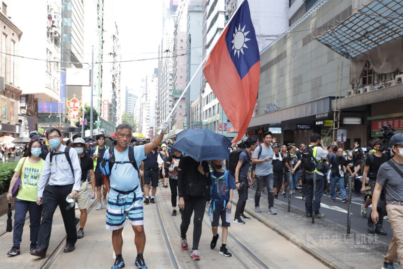 香港爆發反送中運動後，港台關係恐難回到從前。圖為2019年10月1日香港市民上街抗議中共專制統治，其中有人舉起中華民國國旗。（中央社檔案照片）