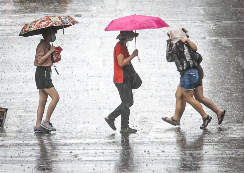 中央氣象局預報，7月2日起至8日，台灣受低壓帶影響，天氣不穩定，全台防大雨。圖為6月27日台北市民眾撐傘或用衣物遮雨過馬路。（中央社檔案照片）