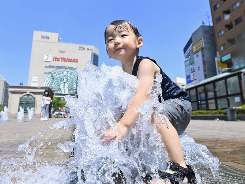 日本東京市中心7月2日中午12時7分出現攝氏35.1度高溫，從6月25日起連續8天被觀測到逾35度的「猛暑日」，追平當地觀測史紀錄。圖為1日男孩在龜有車站前廣場戲水。（共同社）