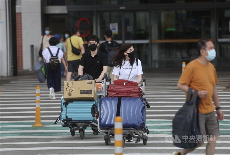 圖為旅客配戴口罩推著行李步出台北松山機場。中央社記者吳家昇攝 111年7月4日