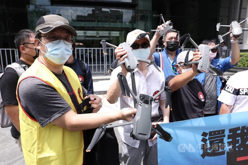 313反不平等空域聯盟4日上午到交通部前舉行記者會,提出自然人可申請夜間飛航(不需法人資格),並希望換照規定也比照機師,延長到5年換照1次。圖為聯盟成員攜帶無人機表達訴求。中央社記者趙世勳攝 111年7月4日