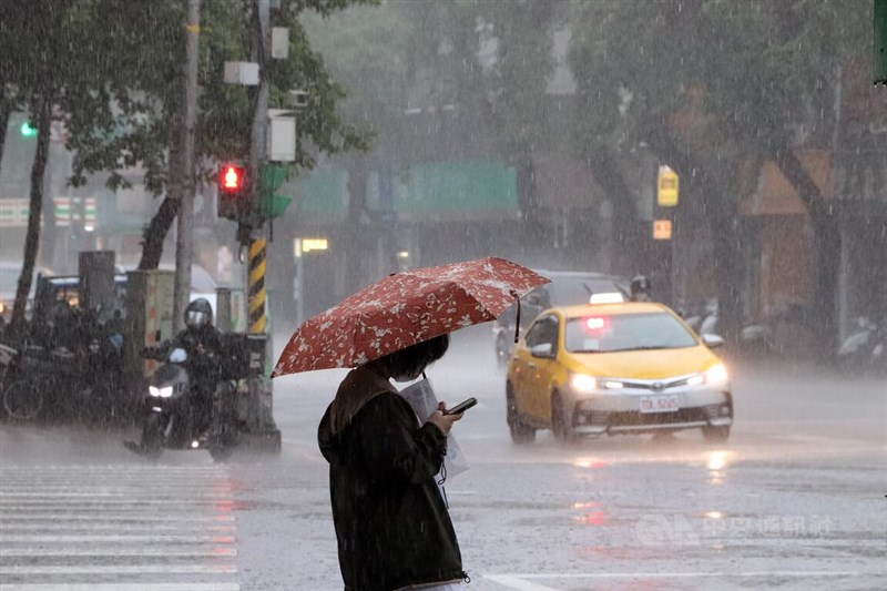 中央氣象局5日中午發布大雨特報，大台北、宜蘭、南部地區及中部以北山區可能有局部大雨發生。圖為4日北市中山區午後降下滂沱大雨，街頭民眾在雨中撐傘前進。（中央社檔案照片）