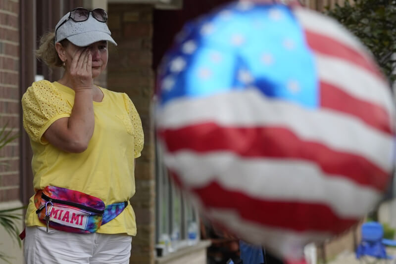 美國伊利諾州高地公園7月4日舉行獨立紀念日遊行時發生槍擊案。圖為現場一名女子在街邊擦眼淚。（美聯社）