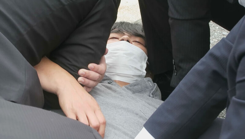 日本前首相安倍晉三8日遭槍擊，嫌犯山上徹也（灰衣者）當場被逮捕。（共同社）