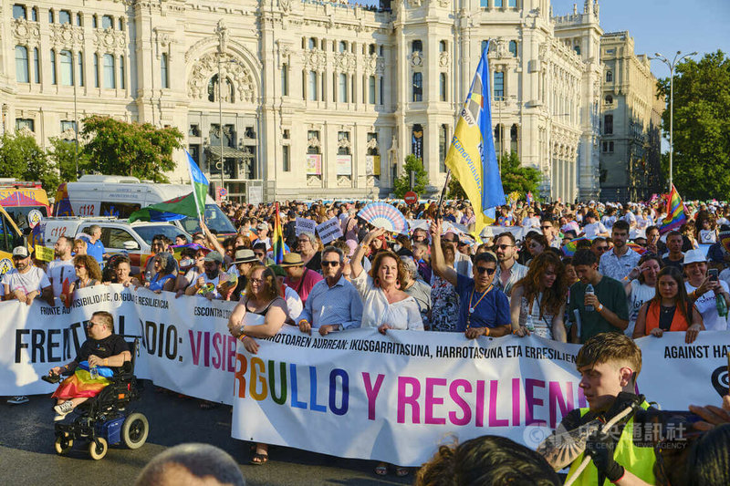 馬德里LGBTI+驕傲大遊行隊伍前鋒，由西班牙首位擔任市議員的變性人士安東內利 （Carla Antonelli）（隊伍第一排身著白衣高舉扇子）打頭陣，拉出印著活動訴求「面對仇恨：能見度、驕傲、抗戰」的長旗。中央社記者胡家綺馬德里攝 111年7月9日