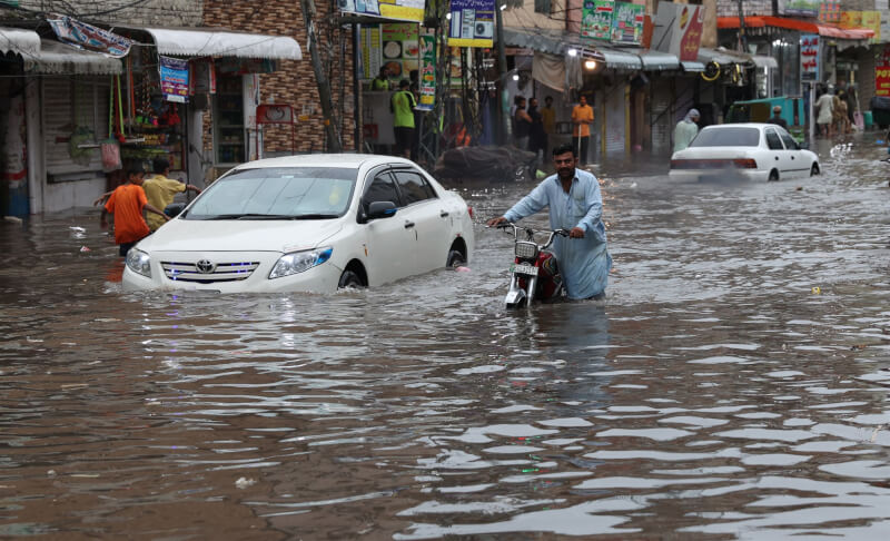 巴基斯坦雨季引發部分地區洪災氾濫，官員指出，過去1個月已有147人死於相關事故。圖為5日巴基斯坦民眾在被洪水淹沒的街道上艱難前行。（安納杜魯新聞社）