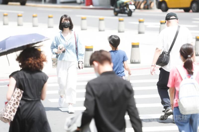 圖為走在台北西門町街頭的民眾撐傘、戴帽子遮陽。（中央社檔案照片）