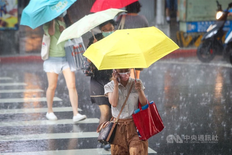 台北市中山區19日午後下起大雷雨，走在街頭的民眾紛紛撐傘遮擋雨勢。中央社記者王騰毅攝 111年7月19日
