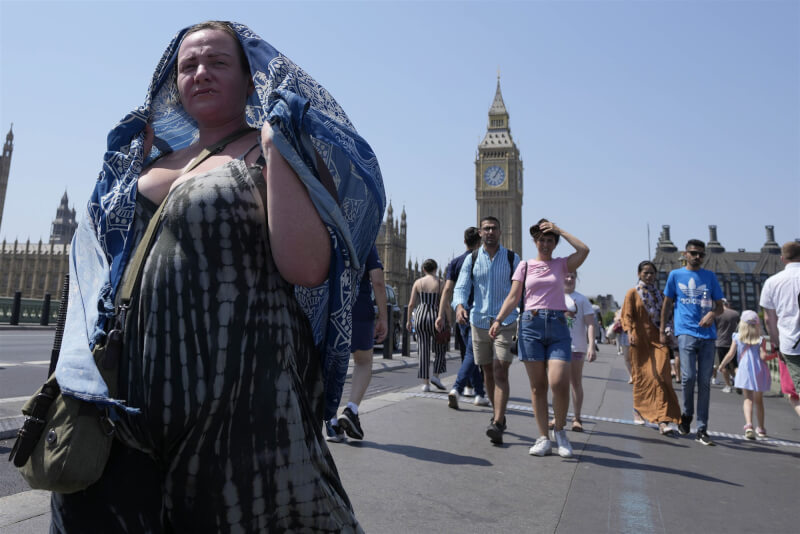 英國19日氣溫首度超過40度。圖為19日倫敦西敏橋行人試圖遮陽。（美聯社）