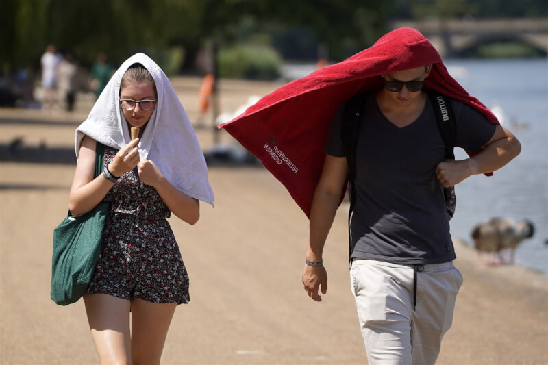 圖為英國倫敦民眾19日以毛巾遮陽。（法新社）