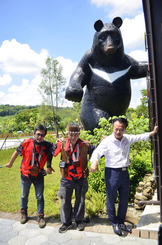 嘉義縣鄒族逐鹿文創園區歷即日起試營運,嘉義縣長翁章梁(右)21日走訪,並與園區內6公尺高的台灣黑熊公仔合影。圖中為逐鹿社區發展協會理事長莊莫俄。中央社記者蔡智明攝 111年7月21日
