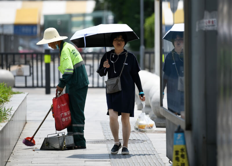 中國氣象局指出，21日起新一波的高溫天氣將影響全中國超過17個省市區，部分南方城市的體感溫度達攝氏60度。圖為江西南昌市，民眾在烈日下撐傘步行。（中新社）