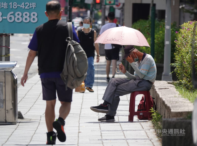 中央氣象局22日上午發布18縣市高溫燈號資訊,雙北及宜蘭、花蓮有連續出現攝氏38度極端高溫的機率。圖為17日民眾在南港車站人行道撐傘遮陽。(中央社檔案照片)