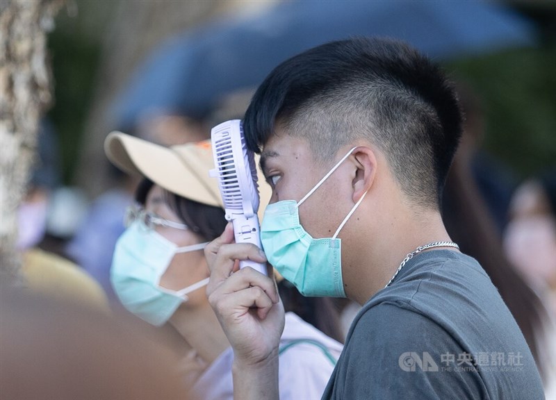 農曆24節氣中的「大暑」到來,全台各地23日高溫炎熱,台北市中正區街頭有民眾拿著隨身小風扇緊貼額頭、吹風降溫。中央社記者謝佳璋攝 111年7月23日