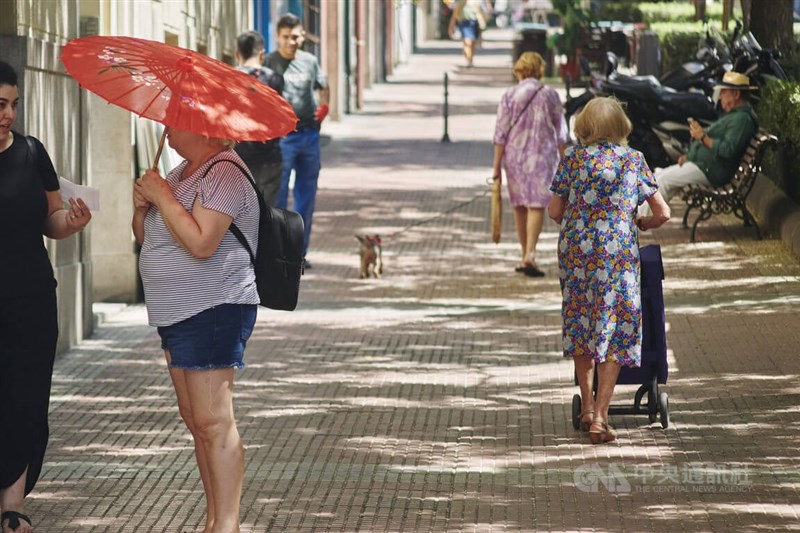 世衛歐洲辦公室22日表示，歐洲受熱浪侵襲，光在西班牙和葡萄牙就有超過1700人死於高溫。圖為西班牙人學亞洲遊客打起傘來遮陽。（中央社檔案照片）