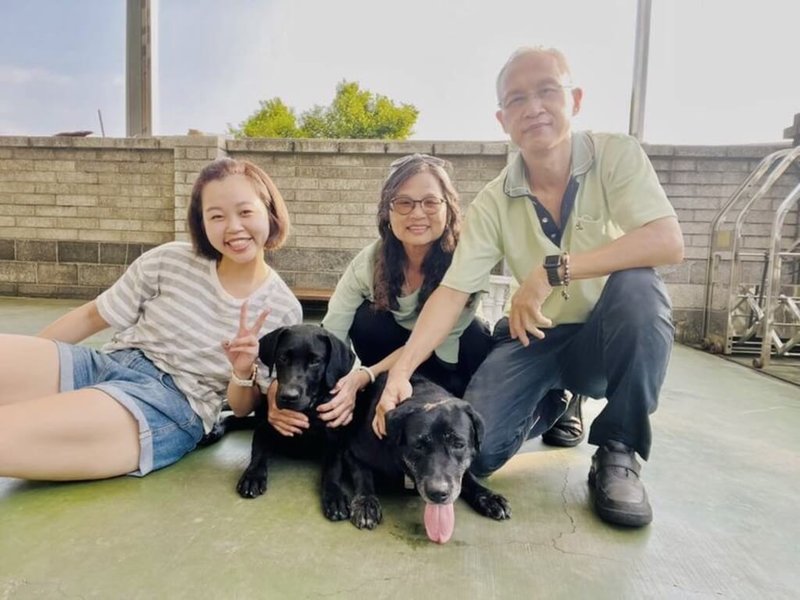 台中市民眾溫惠容(中)一家已擔任海關緝毒犬寄養家庭將近10年。圖為溫惠容與女兒、丈夫,和目前寄養犬隻Wiki、退役母種犬Xena。(寄養家庭溫惠容提供)中央社記者張璦傳真 111年7月24日