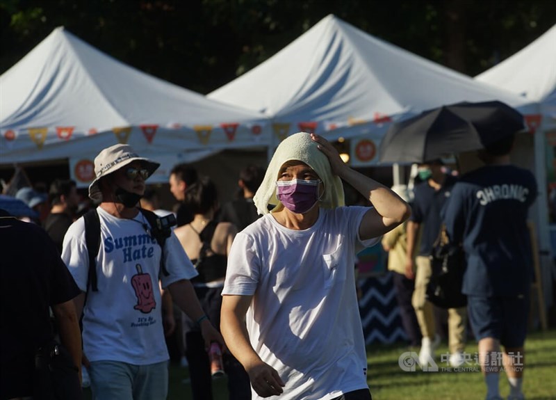 天母運動公園內滿是人潮,有民眾以毛巾披頭,遮陽防曬。中央社記者裴禛攝 111年7月23日